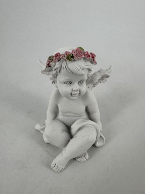 Ange assis avec fleurs roses regarde vers la gauche